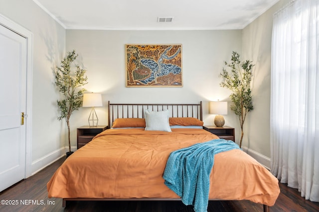 bedroom with baseboards, crown molding, visible vents, and wood finished floors