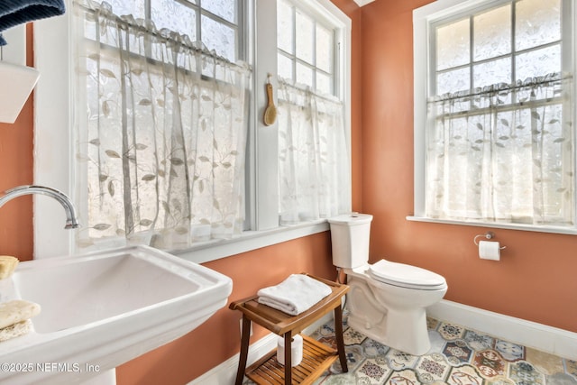 bathroom with toilet, baseboards, a sink, and tile patterned floors