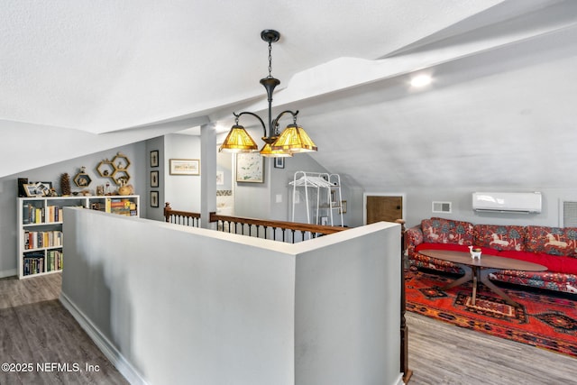 interior space featuring visible vents, vaulted ceiling, wood finished floors, and a wall mounted air conditioner