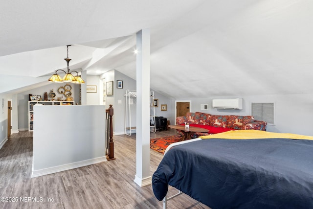 bedroom with wood finished floors, visible vents, baseboards, vaulted ceiling, and a wall mounted air conditioner