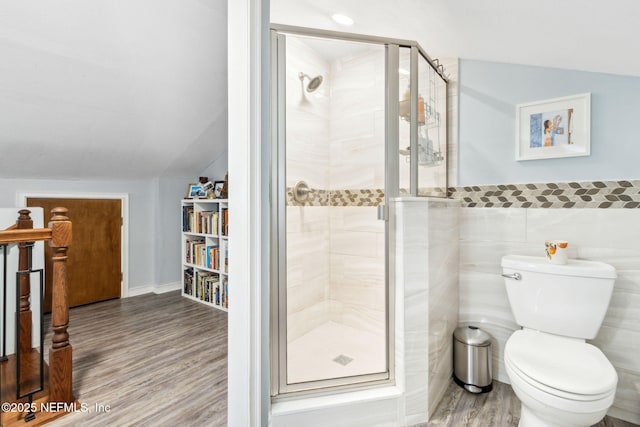 bathroom with vaulted ceiling, a shower stall, and wood finished floors