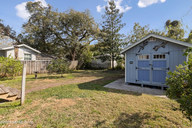 view of yard with a fenced backyard, a storage unit, and an outbuilding