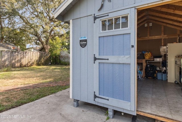 view of outdoor structure with fence and an outbuilding