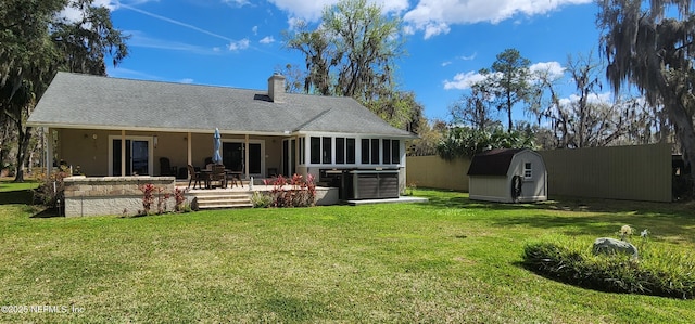 rear view of house featuring an outdoor structure, a lawn, a shed, a chimney, and a patio area