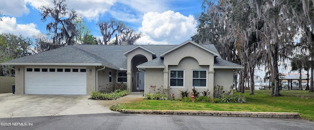 single story home with stucco siding, a shingled roof, concrete driveway, a front yard, and a garage