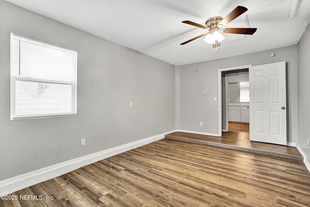 unfurnished bedroom featuring a ceiling fan, multiple windows, baseboards, and wood finished floors