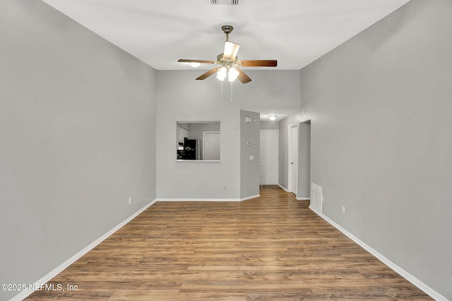 unfurnished living room featuring ceiling fan, lofted ceiling, wood finished floors, visible vents, and baseboards