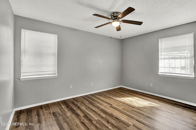 spare room with a textured ceiling, wood finished floors, and baseboards