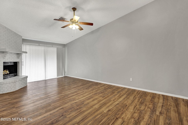 unfurnished living room featuring visible vents, a ceiling fan, wood finished floors, a textured ceiling, and a fireplace