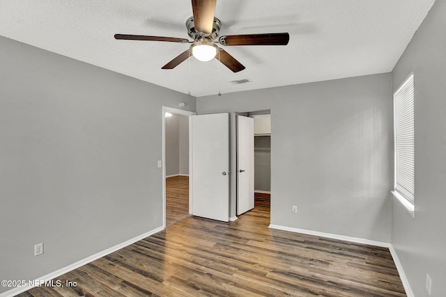 unfurnished bedroom with baseboards, a textured ceiling, visible vents, and wood finished floors