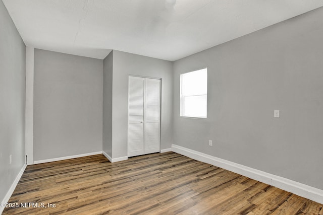 unfurnished bedroom featuring a closet, baseboards, and wood finished floors