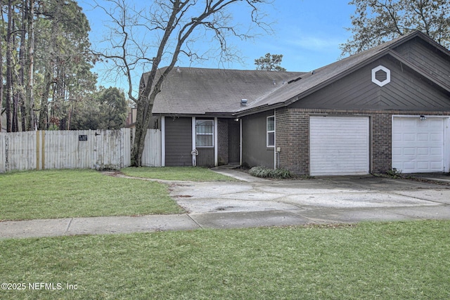 view of front facade with brick siding, an attached garage, a front yard, fence, and driveway