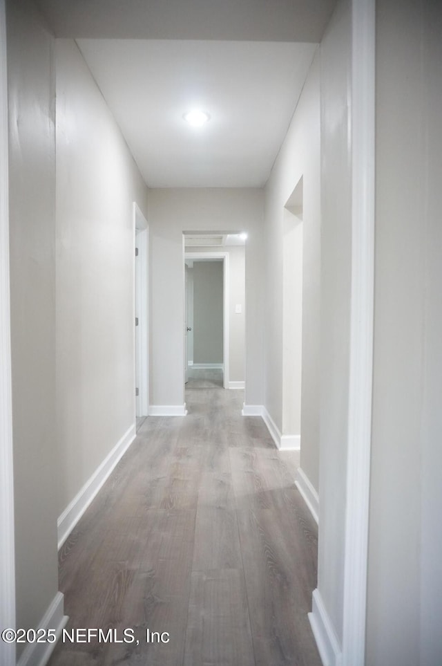 corridor featuring wood finished floors and baseboards