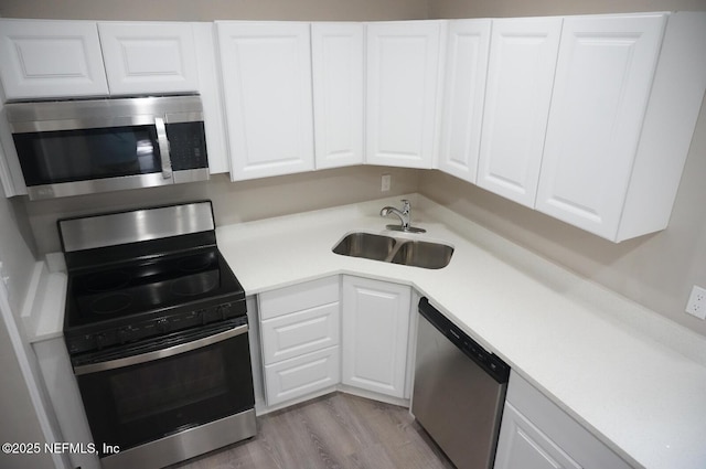 kitchen with appliances with stainless steel finishes, white cabinets, a sink, and light countertops