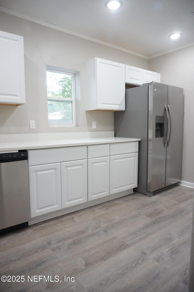 kitchen featuring crown molding, appliances with stainless steel finishes, light wood-style flooring, and white cabinets