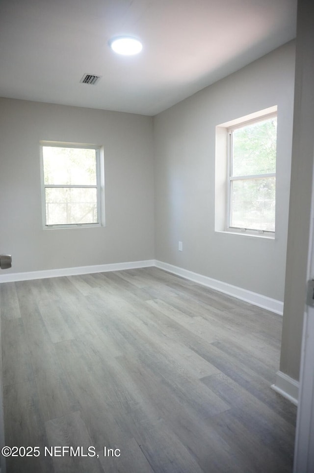 empty room with visible vents, baseboards, and wood finished floors