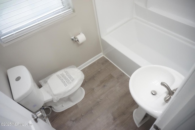 full bath featuring baseboards, a shower, toilet, wood finished floors, and a sink