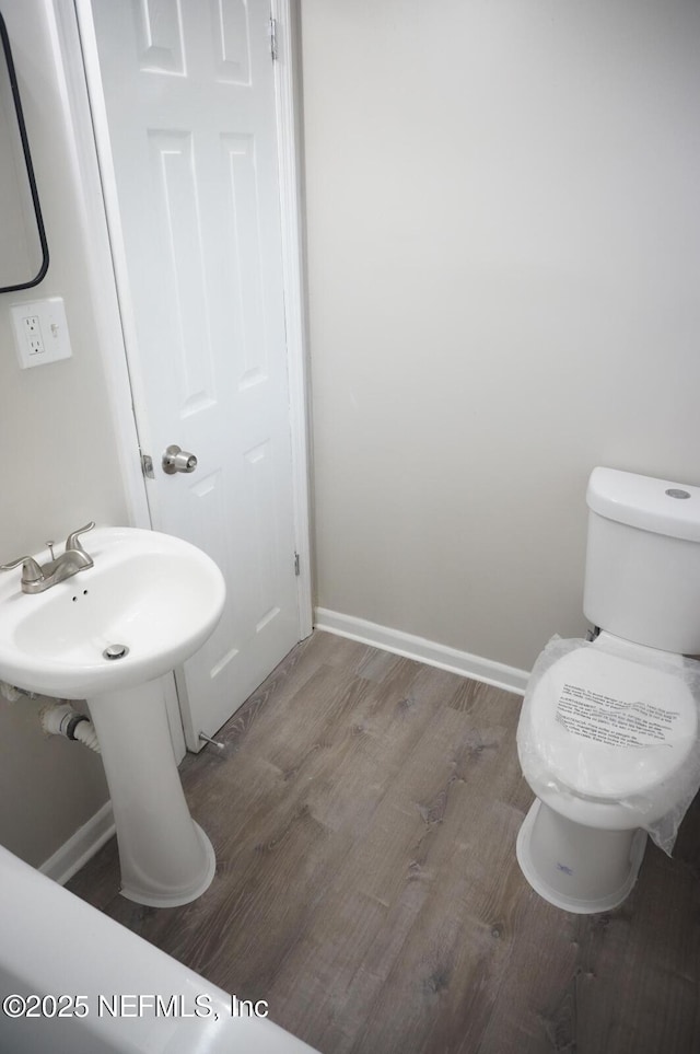 bathroom with wood finished floors, toilet, and baseboards