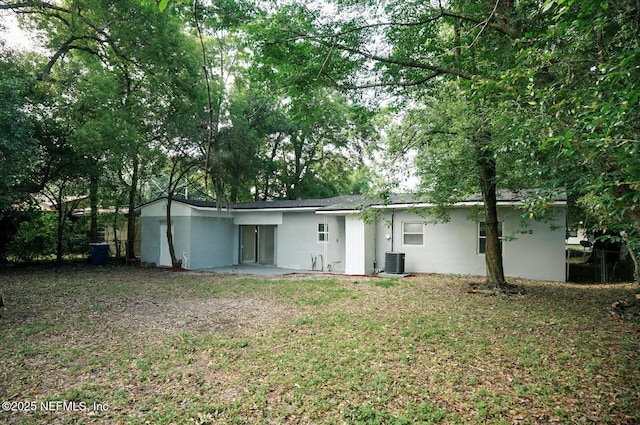 back of house featuring central air condition unit and stucco siding