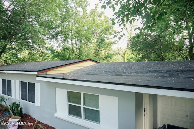 exterior details with stucco siding and roof with shingles