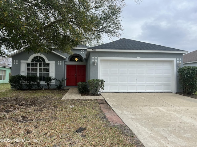 ranch-style house with a shingled roof, driveway, an attached garage, and stucco siding