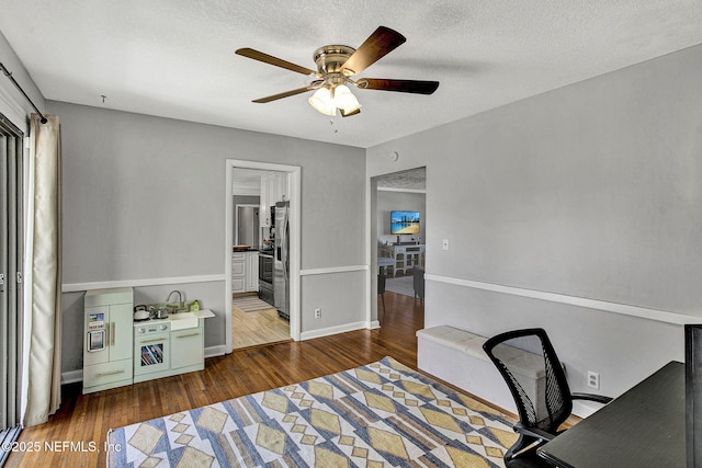 office featuring ceiling fan, a textured ceiling, wood finished floors, and baseboards