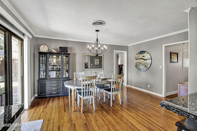 dining room with hardwood / wood-style flooring, visible vents, an inviting chandelier, and ornamental molding