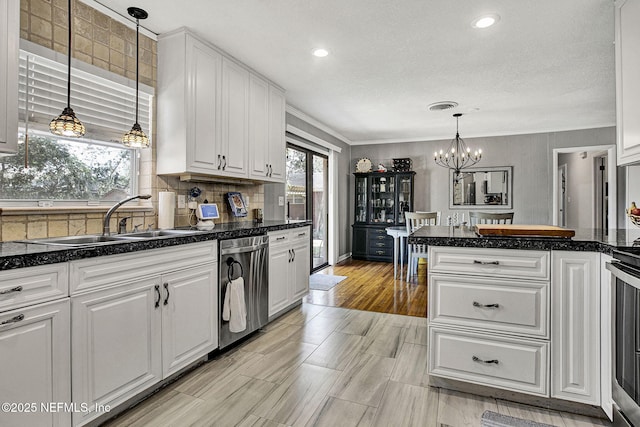 kitchen with stainless steel dishwasher, a healthy amount of sunlight, a sink, and white cabinets