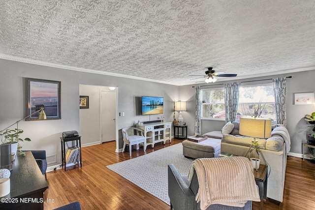 living area with a ceiling fan, crown molding, baseboards, and wood finished floors