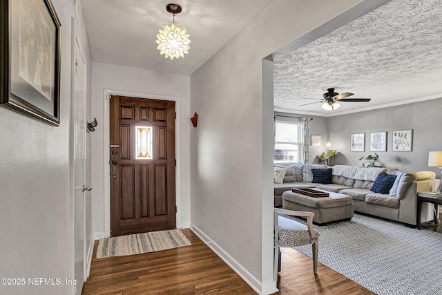 entryway with dark wood-style floors, a textured ceiling, ceiling fan with notable chandelier, and baseboards