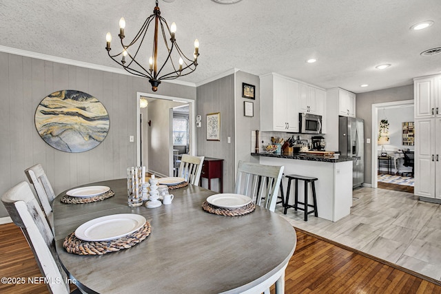 dining room featuring visible vents, crown molding, light wood-style flooring, and a textured ceiling