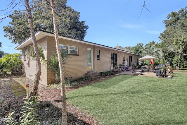 rear view of house with entry steps, crawl space, a yard, and a patio