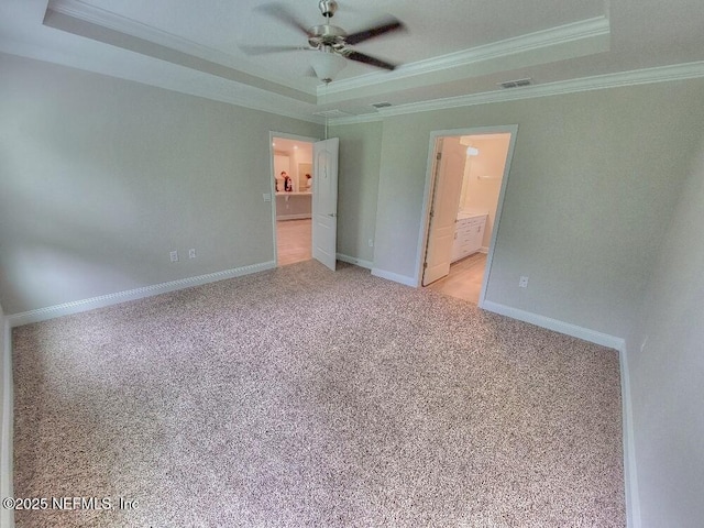 unfurnished bedroom featuring ornamental molding, a tray ceiling, light colored carpet, and baseboards