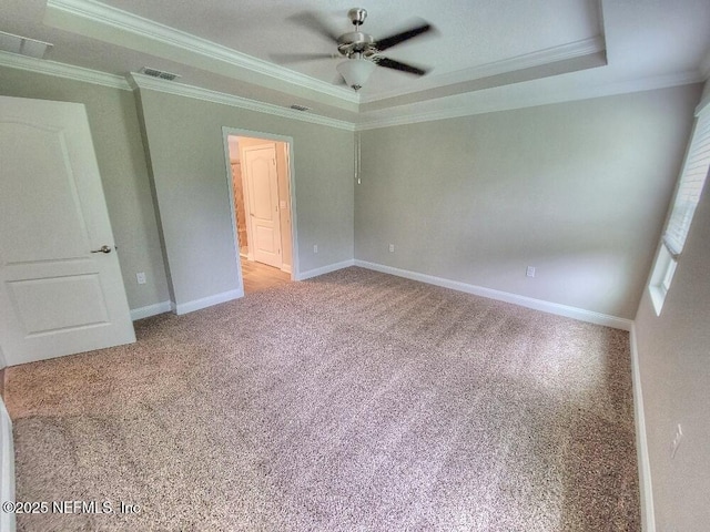 unfurnished bedroom with crown molding, visible vents, a raised ceiling, and carpet flooring