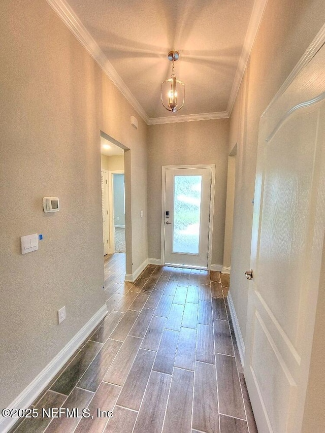 doorway to outside with baseboards, a chandelier, crown molding, and wood finish floors