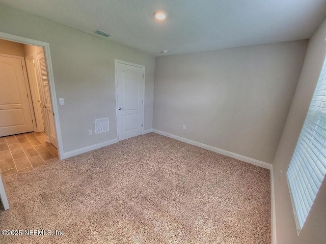 unfurnished bedroom with light carpet, baseboards, and visible vents