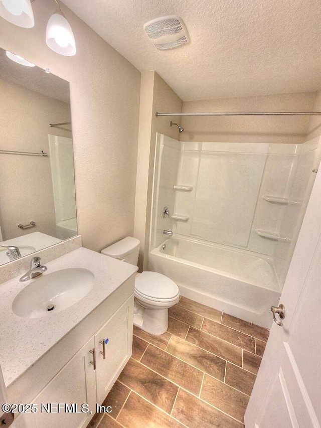 bathroom featuring visible vents, toilet, wood tiled floor, a textured ceiling, and vanity