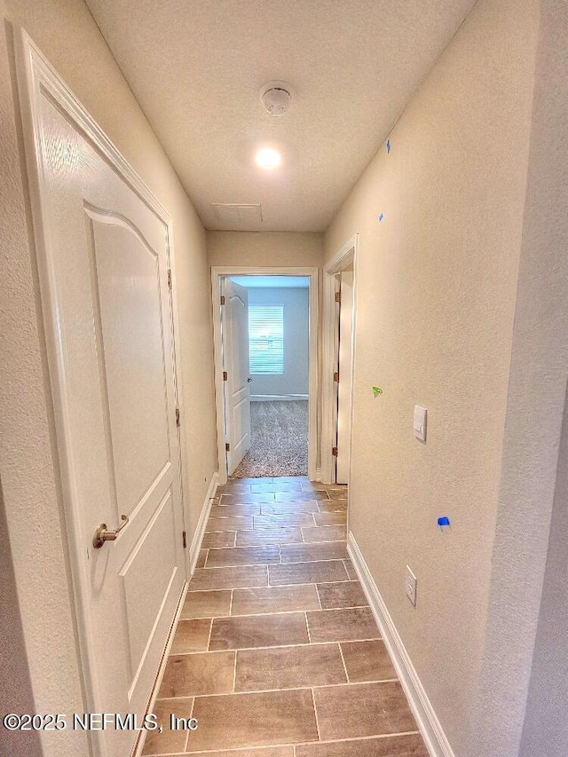 corridor with wood finish floors and baseboards