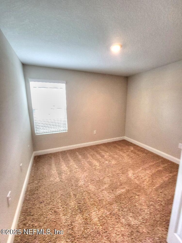 carpeted spare room featuring a textured ceiling and baseboards