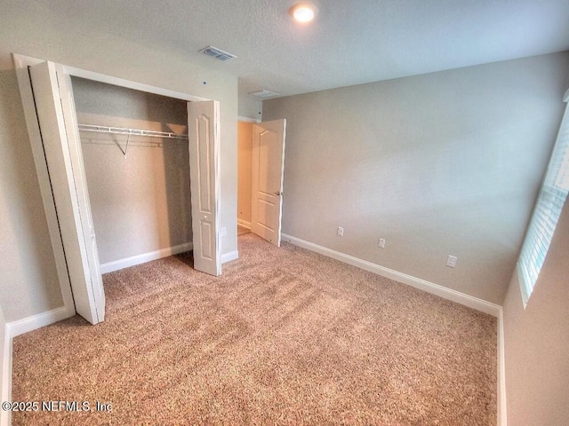 unfurnished bedroom with baseboards, a closet, visible vents, and carpet flooring