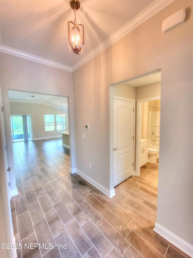 empty room with an inviting chandelier, crown molding, and wood finish floors