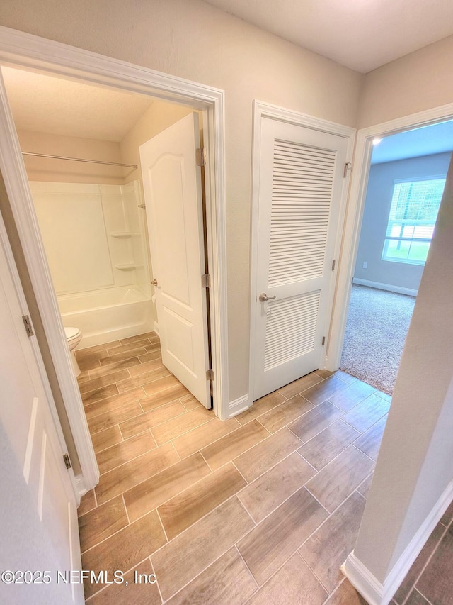 corridor featuring wood tiled floor and baseboards