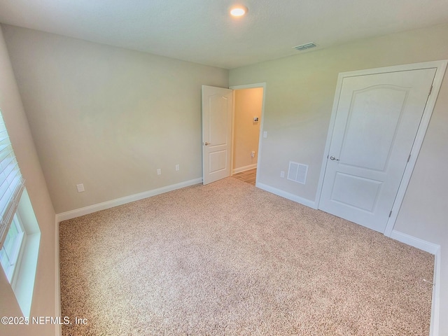 unfurnished bedroom with carpet floors, baseboards, and visible vents