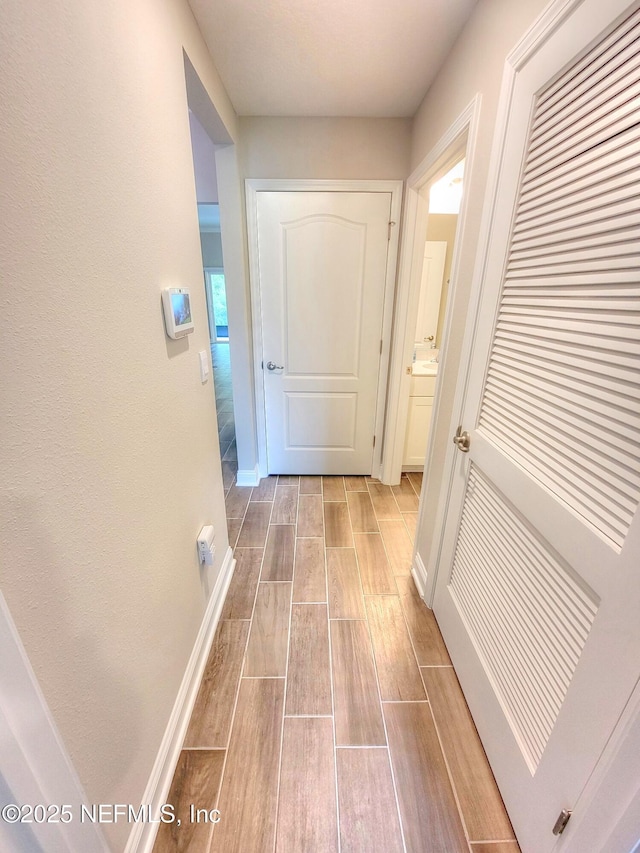 corridor with wood tiled floor and baseboards