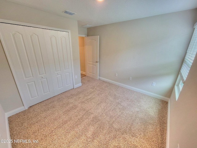 unfurnished bedroom featuring carpet floors, baseboards, visible vents, and a closet