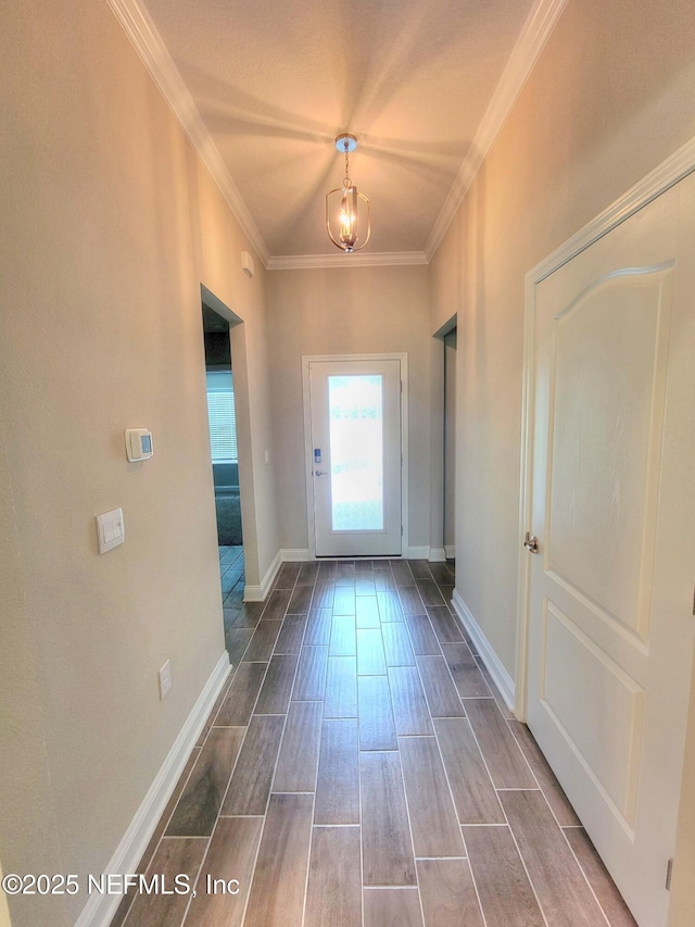 doorway featuring an inviting chandelier, baseboards, crown molding, and wood finish floors