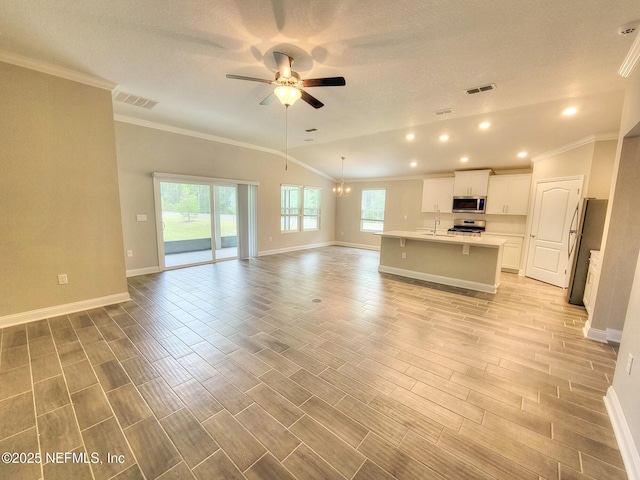 kitchen featuring stainless steel appliances, wood finish floors, a sink, open floor plan, and light countertops