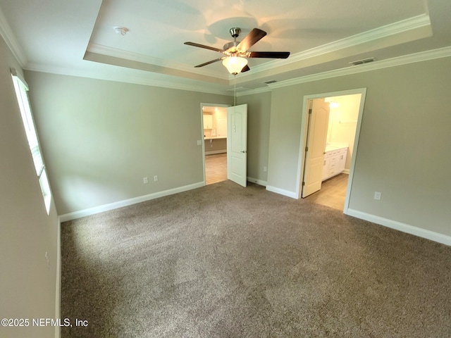 unfurnished bedroom featuring carpet, visible vents, a tray ceiling, and crown molding