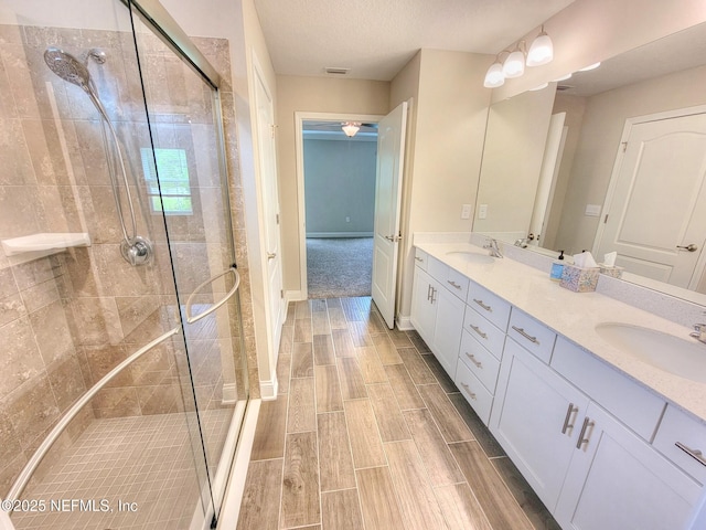 full bath featuring double vanity, a stall shower, a sink, and wood finish floors