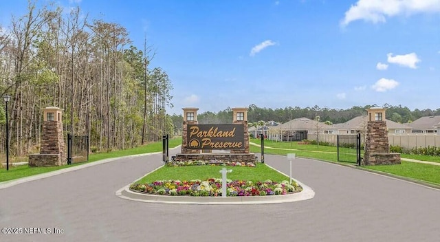 community / neighborhood sign featuring driveway, a residential view, fence, and a yard